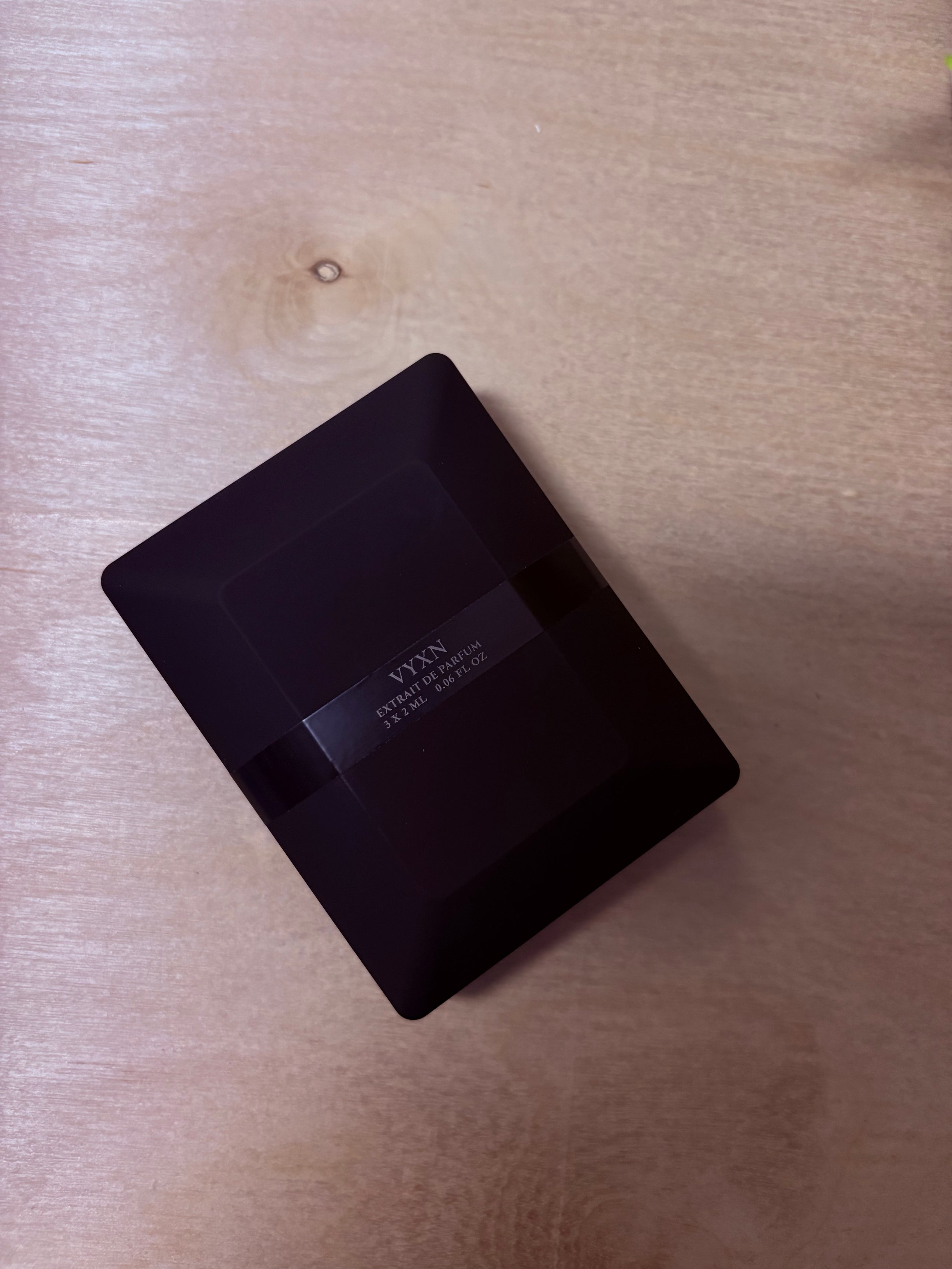 Black rectangular product with 'VYXN' branding on a wooden surface