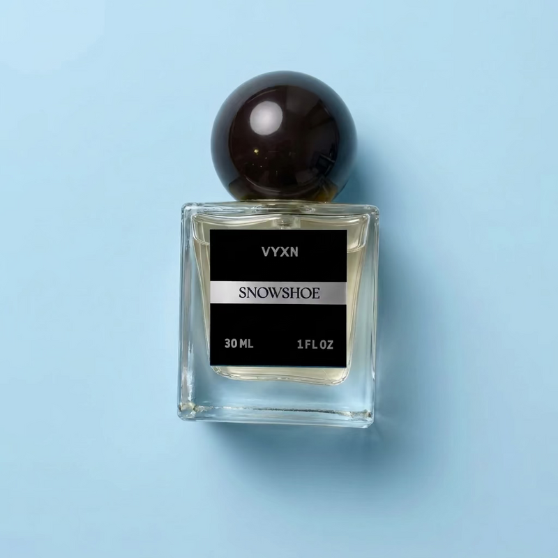 Perfume bottle labeled VYXN SNOWSHOE 30 ml 1 fl.oz. background white silk. label is back and silver