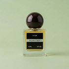 A 30 ml bottle of VYXN Maine Coon fragrance, featuring a clear glass bottle with yellow-amber liquid, a black label, and a dark marbled spherical cap, set against a draped light pink satin fabric background.